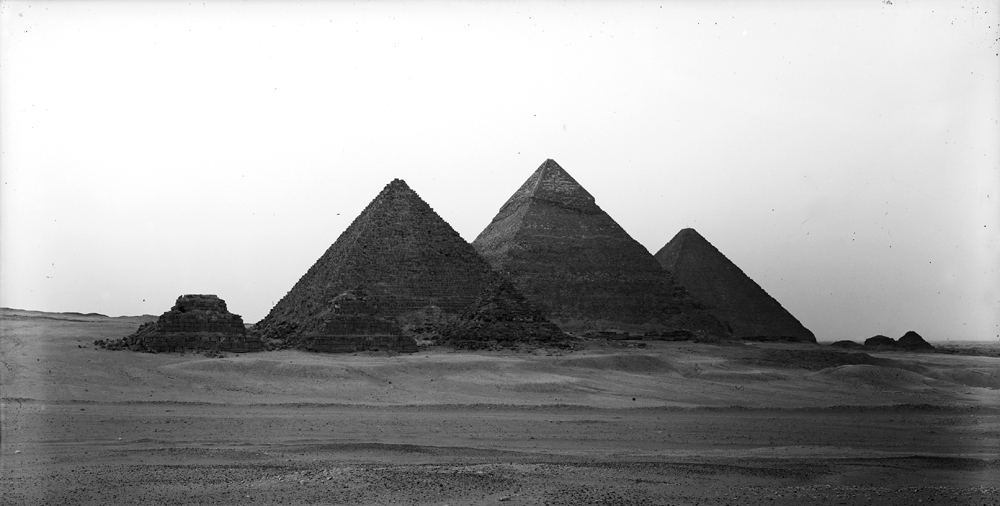 Black and white photo of all 3 pyramids across the sand